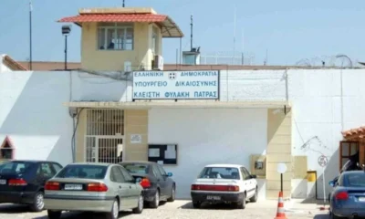 Εξωτερική άποψη κτιρίου με πινακίδα που αναγράφει Υπουργείο Δικαιοσύνης, με σταθμευμένα αυτοκίνητα μπροστά.