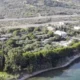 Αεροφωτογραφία παράκτιας έκτασης με δέντρα, κτίσματα και δρόμο στο βάθος