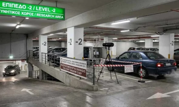 Υπόγειος χώρος στάθμευσης με σταθμευμένα αυτοκίνητα, επιστημονικό εξοπλισμό και πινακίδα σήμανσης.