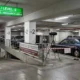 Υπόγειος χώρος στάθμευσης με σταθμευμένα αυτοκίνητα, επιστημονικό εξοπλισμό και πινακίδα σήμανσης.