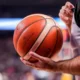 Διαιτητής κρατάει μπάλα μπάσκετ με τα χέρια του μέσα σε γήπεδο