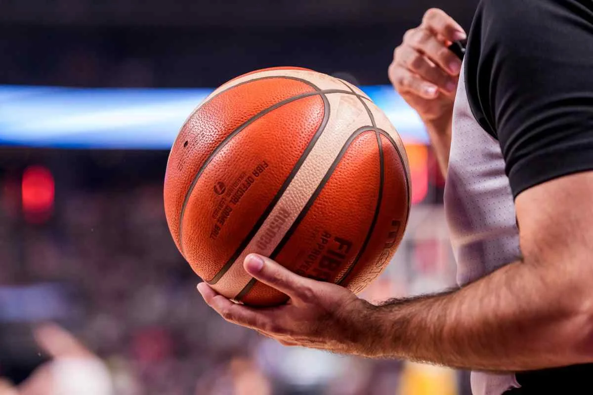 Διαιτητής κρατάει μπάλα μπάσκετ με τα χέρια του μέσα σε γήπεδο
