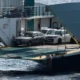 Αυτοκίνητα σταθμευμένα στο γκαράζ πλοίου με ανοιχτό καταπέλτη πάνω στη θάλασσα