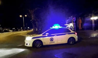 Περιπολικό όχημα σταθμευμένο σε δρόμο τη νύχτα με αναμμένους φάρους.