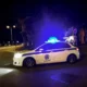 Περιπολικό όχημα σταθμευμένο σε δρόμο τη νύχτα με αναμμένους φάρους.