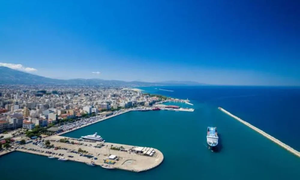 Πανοραμική άποψη λιμανιού και παράκτιας πόλης με πλοίο στη θάλασσα κάτω από γαλάζιο ουρανό.