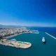 Πανοραμική άποψη λιμανιού και παράκτιας πόλης με πλοίο στη θάλασσα κάτω από γαλάζιο ουρανό.