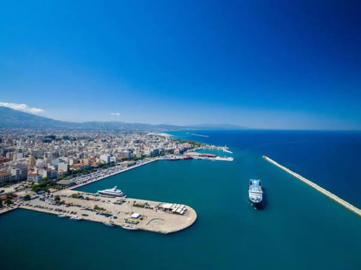 Πανοραμική άποψη λιμανιού και παράκτιας πόλης με πλοίο στη θάλασσα κάτω από γαλάζιο ουρανό.