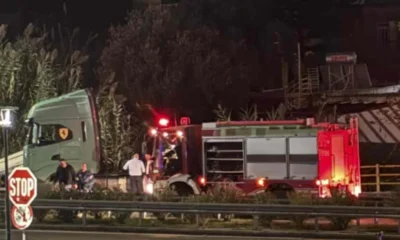 Νυχτερινή λήψη με πυροσβεστικό όχημα και άτομα κοντά σε δρόμο με πινακίδα στοπ.