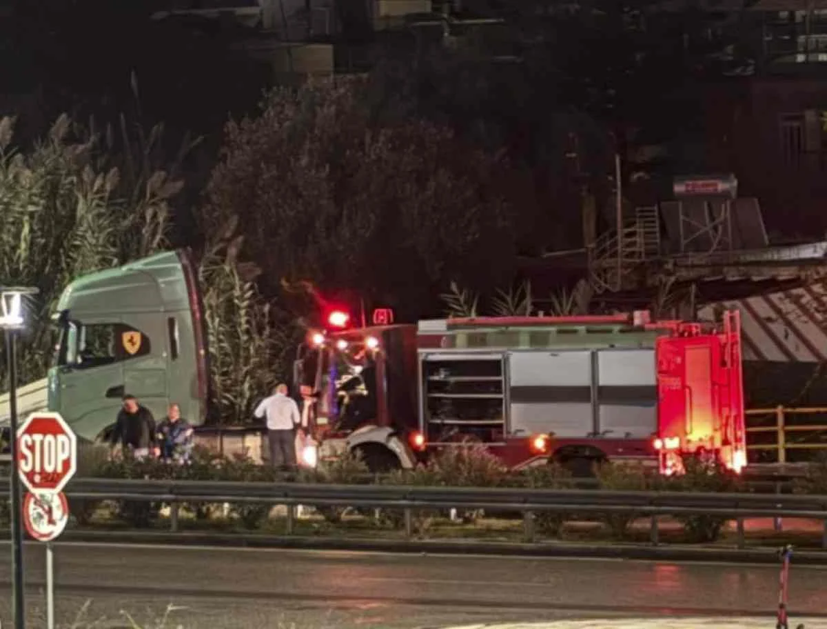 Νυχτερινή λήψη με πυροσβεστικό όχημα και άτομα κοντά σε δρόμο με πινακίδα στοπ.