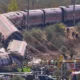 Εκτροχιασμένα και κατεστραμμένα βαγόνια τρένου σε πρανές, με πλήθος κόσμου και οχήματα έκτακτης ανάγκης στο σημείο.