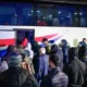 Πλήθος ατόμων με κουκούλες και σακίδια πλάτης επιβιβάζονται σε λεωφορείο