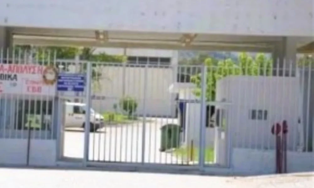 Είσοδος φυλασσόμενου κτιρίου με μεταλλική θύρα και φυλάκιο.