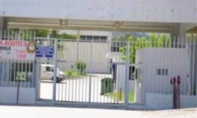 Είσοδος φυλασσόμενου κτιρίου με μεταλλική θύρα και φυλάκιο.