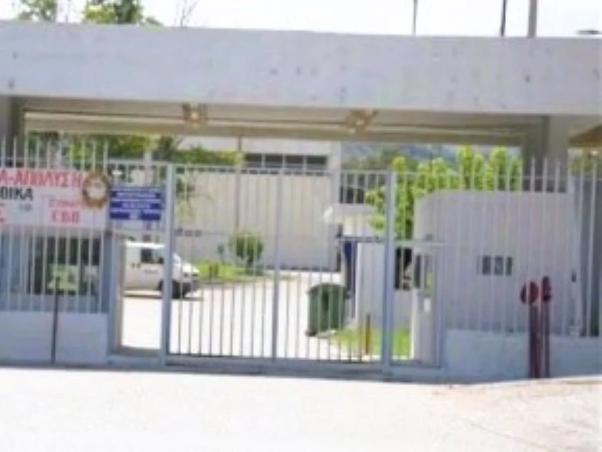 Είσοδος φυλασσόμενου κτιρίου με μεταλλική θύρα και φυλάκιο.