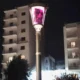 Φωτιστικός στύλος με μουτζουρωμένο φως τη νύχτα και πολυκατοικίες στο βάθος.