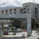 Εξωτερική άποψη κτιρίου νοσοκομείου με είσοδο, πινακίδα, αυτοκίνητα και σκύλο στον δρόμο