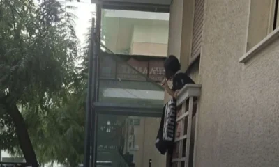 Άτομο σε μπαλκόνι κτιρίου κρατάει αντικείμενο