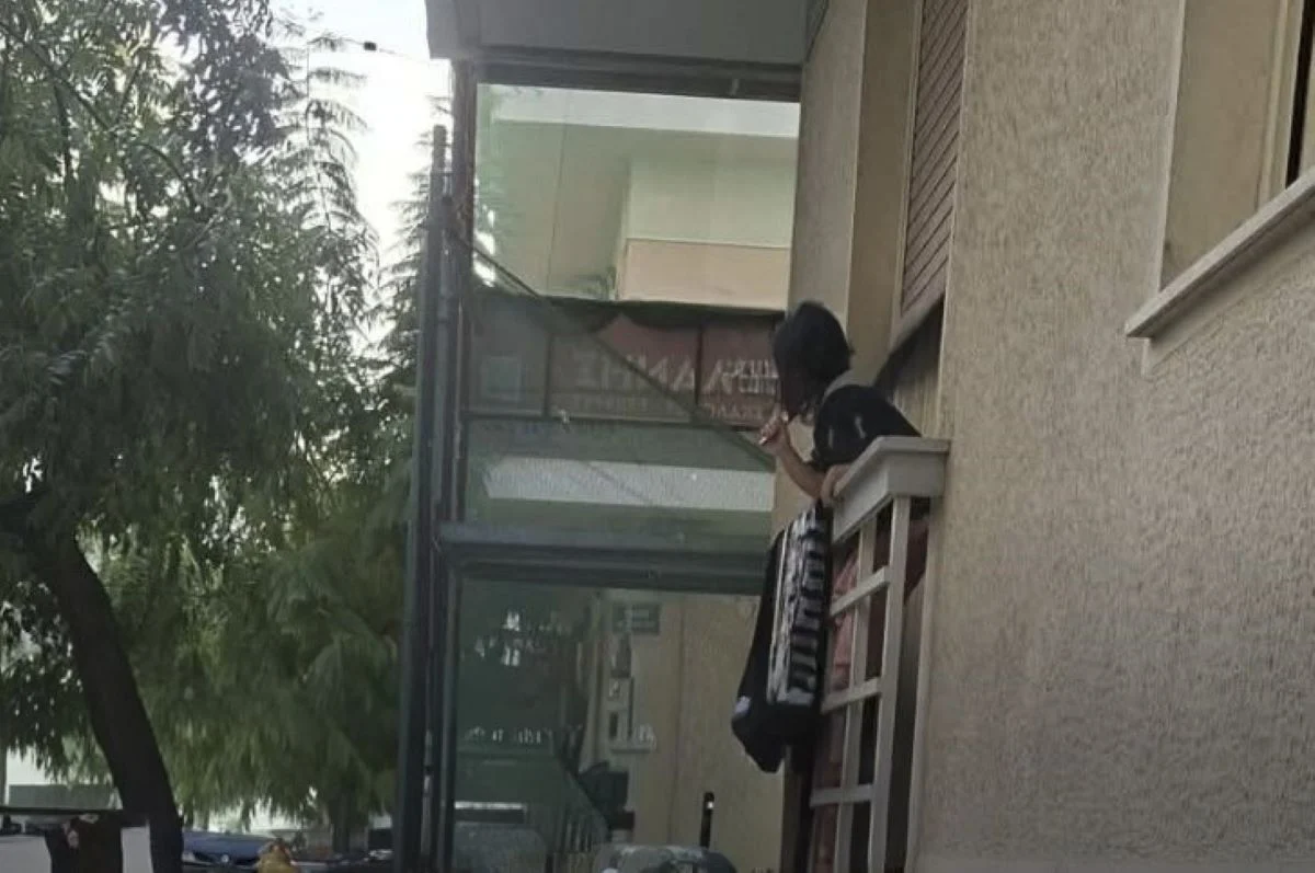 Άτομο σε μπαλκόνι κτιρίου κρατάει αντικείμενο
