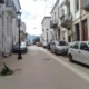Άποψη στενού δρόμου ανάμεσα σε κτήρια με παρκαρισμένα αυτοκίνητα δεξιά και αριστερά.