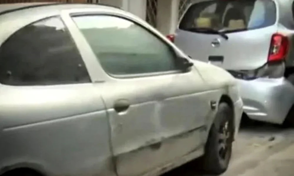 Δύο ασημί αυτοκίνητα σταθμευμένα σε δρόμο, με ορατές φθορές στο αμάξωμα.