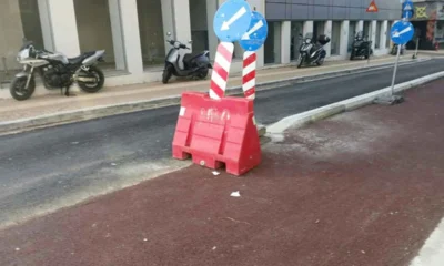 Δρόμος με κόκκινο διάδρομο, πορτοκαλί πλαστικό εμπόδιο και μπλε πινακίδες σήμανσης.