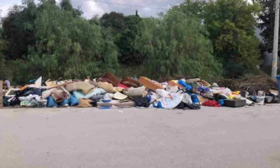 Σωρός από ογκώδη αντικείμενα, έπιπλα και απορρίμματα σε άσφαλτο μπροστά από δέντρα