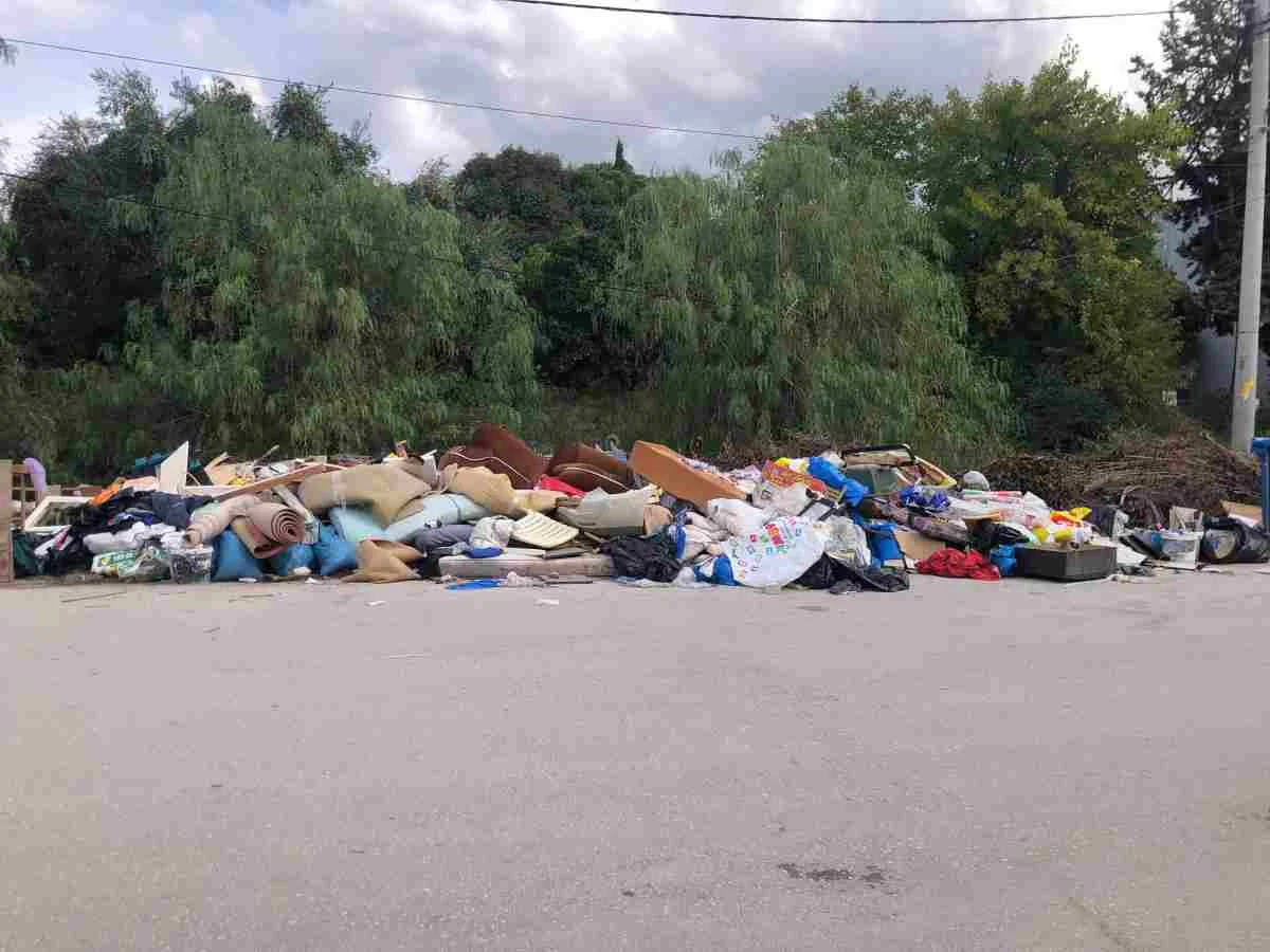 Σωρός από ογκώδη αντικείμενα, έπιπλα και απορρίμματα σε άσφαλτο μπροστά από δέντρα